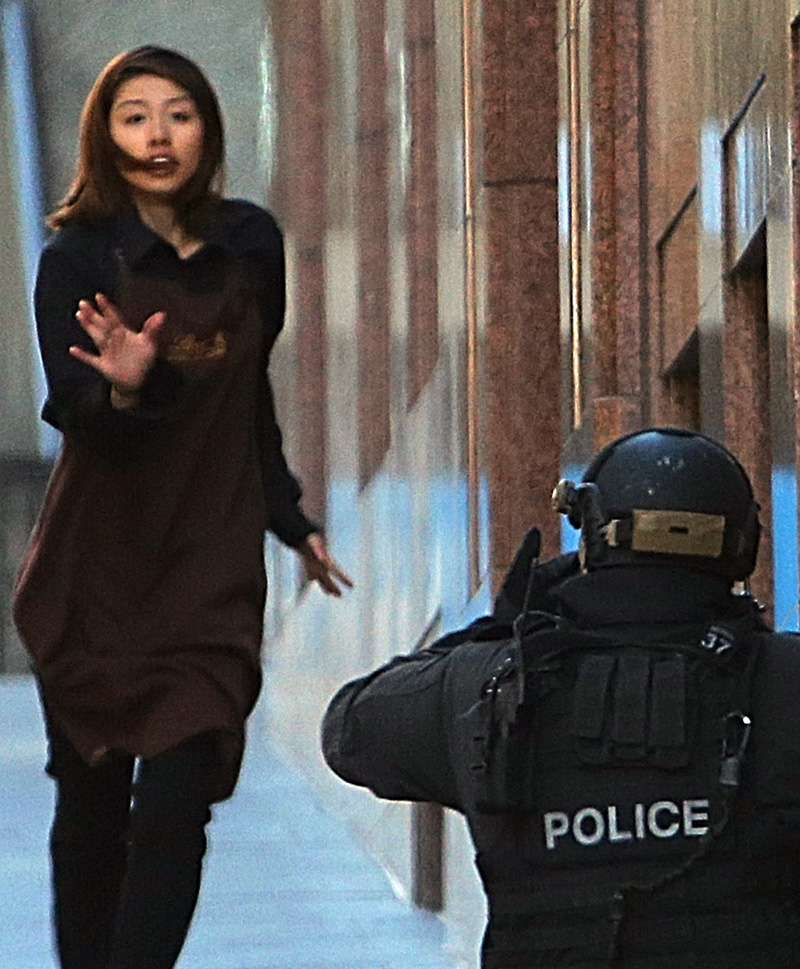 A hostage fleeing from a cafe under siege runs towards an armed tactical response police officer at Martin Place in the central business district of Sydney, Australia.