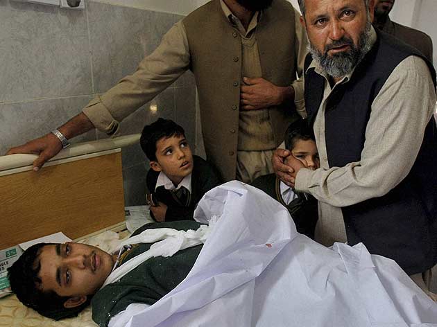 A Pakistani man comforts a student standing at the bedside of a boy who was injured in a Taliban attack on a school, at a local hospital in Peshawar, Pakistan. (AP)