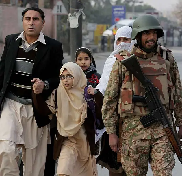 Pakistani parents escort their children outside a school attacked by the Taliban in Peshawar, Pakistan. (AP)
