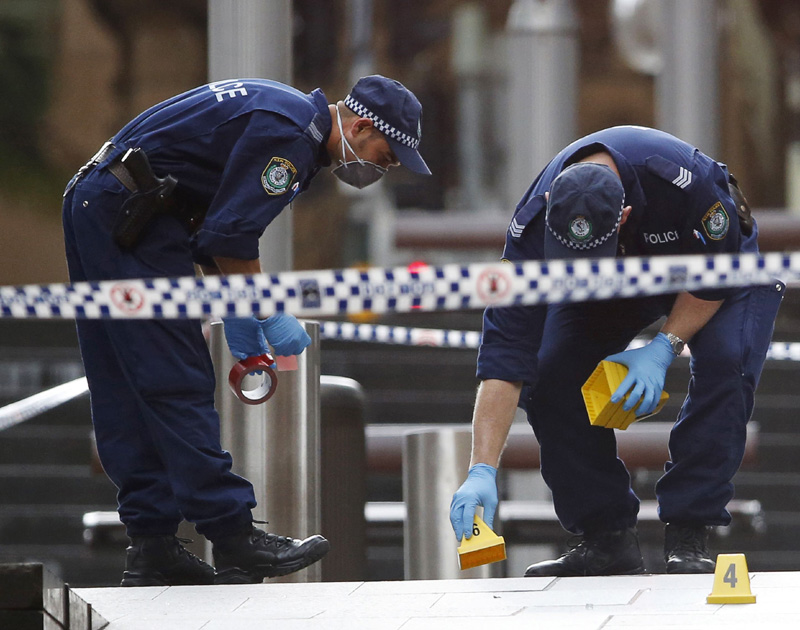 New South Wales police officers wear protective masks as they place marker cones over potential evidence in their investigation into the cafe siege, Sydney, Australia.