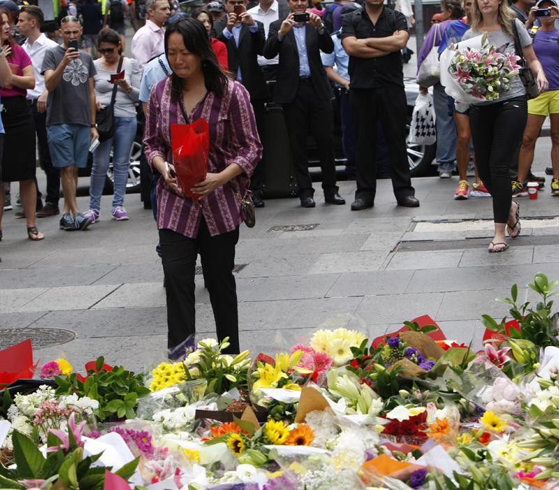 A woman cries as she visits a makeshift memorial in Sydney, Australia Tuesday, Dec. 16, 2014 near where three people died in a siege.