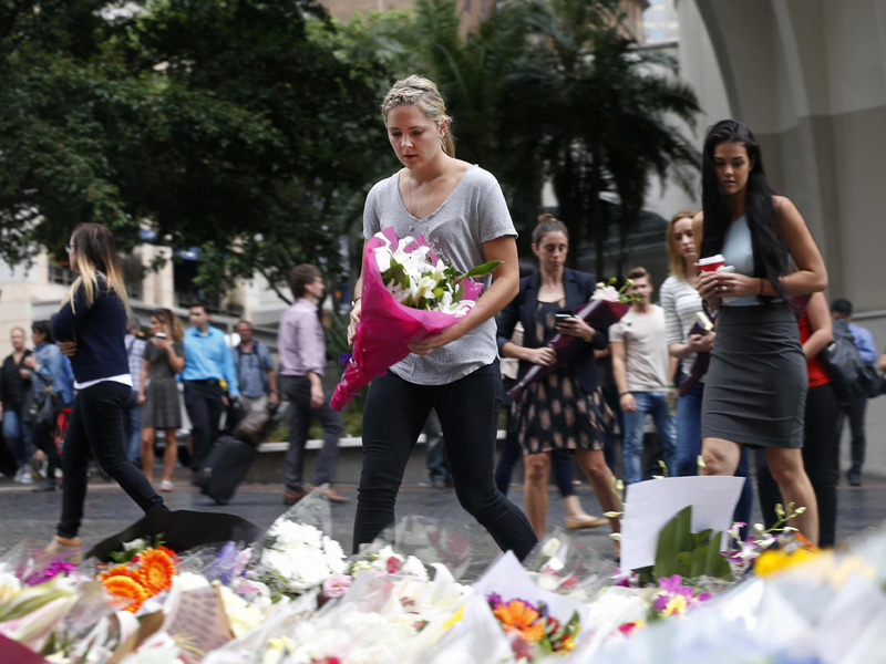 A woman places a floral tribute for those who died in the Sydney cafe siege, near the site of the incident, in Martin Place December 16, 2014.