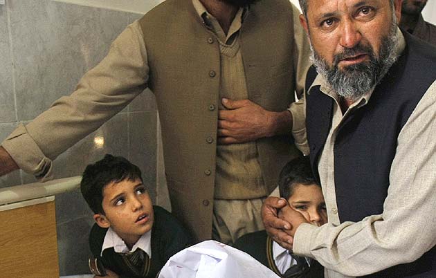 A Pakistani man comforts a student standing at the bedside of a boy who was injured in a Taliban attack on a school that killed more than 100 people, at a local hospital in Peshawar. (AP)