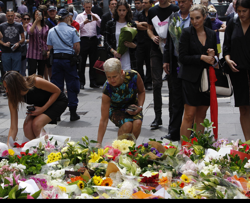Women offer flowers at a makeshift memorial in Sydney, Australia on Dec. 16, 2014 near where three people died in a siege. An Iranian-born gunman took 17 people hostage at a central city cafe Monday before police stormed the cafe early Tuesday. The gunman and two hostages were killed.