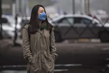 A foreign tourist wears a mask to protect herself from pollutants while walking on a sideway in New Delhi, India, Friday, Jan. 23, 2015. When U.S. President Barack Obama visits New Delhi from Sunday, he will join the Indian capital's masses in breathing some of the world's filthiest air. Hazy skies will serve as the backdrop to meetings with Indian Prime Minister Narendra Modi and other officials who are expected to discuss India's biggest environmental woes: Heavy reliance on fossil fuels that has transformed New Delhi into the planet's most polluted capital and made India the third biggest national emitter of greenhouse gases. (AP)