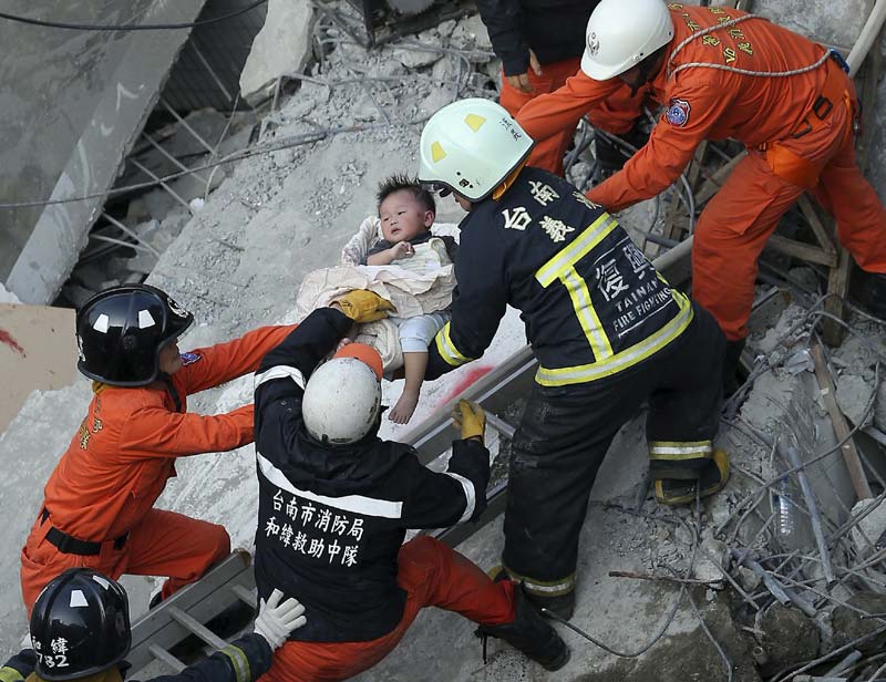 Earthquake in Taiwan: Local authorities said Saturday night that more than 100 people remained missing and that rescuers were racing to find them. Taiwan's official Central News Agency reported that 172 people were missing. <br>Image Caption: Rescue personnel help a child rescued at the site where a 17-storey apartment building collapsed during an earthquake in Tainan, southern Taiwan (Reuters)</br>