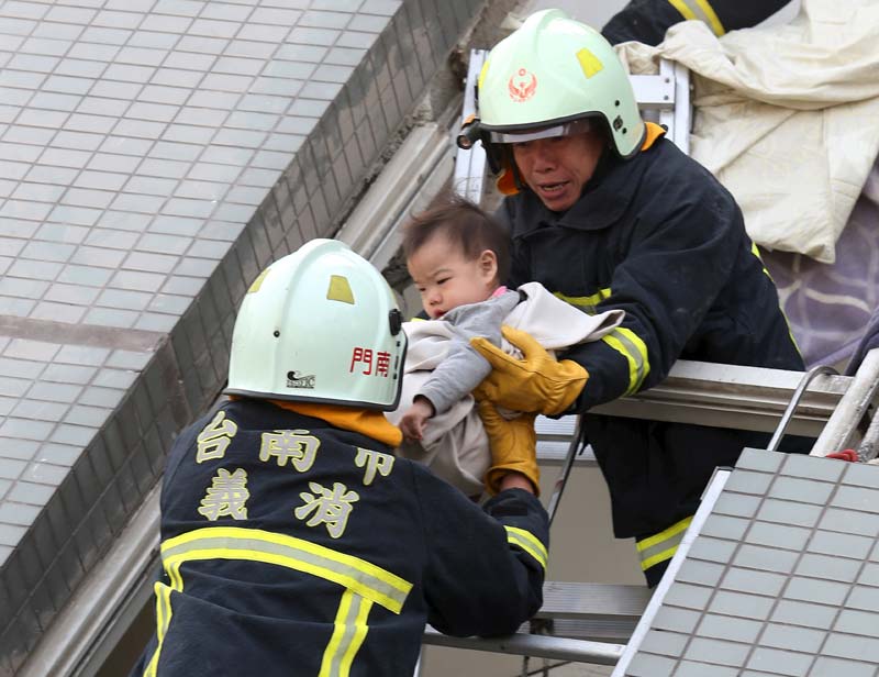 Earthquake in Taiwan: Most people were caught asleep when the earthquake of magnitude 6.4 on Richter scale occurred at about 4 a.m., 22 miles (35 kilometers) southeast of Yujing in Tainan. It struck only 6 miles (10 kilometers) underground, according to the U.S. Geological Survey. Rescuers were searching late Saturday for more than 100 people still missing after the powerful, shallow earthquake struck before dawn and caused a high-rise residential building to collapse, killing at least 12 people and injuring hundreds. Residents in mainland China also reported that the tremor was felt there. <br>Image Caption: Rescuers stand on a ledge of a collapsed building as one of them carries a 10-day-old baby after an earthquake hit the southern city of Tainan, Taiwan (Reuters)</br>