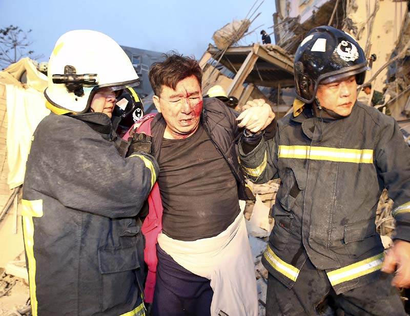 Earthquake in Taiwan: Rescuers found the bodies of a 10-day-old infant, three other children and six adults at the collapsed building, the information center said. One other death was reported at the site, but details were not immediately available. Authorities said two people were killed by falling objects elsewhere in Tainan.<br>Image Caption: Rescue workers carry out a man from the site where a 17-storey apartment building collapsed after an earthquake hit Tainan (Reuters)</br>