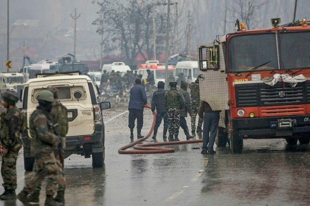 Firemen spray water on the road to wash away the blood stains at the site of suicide bomb attack in Pulwama (PTI Photo)