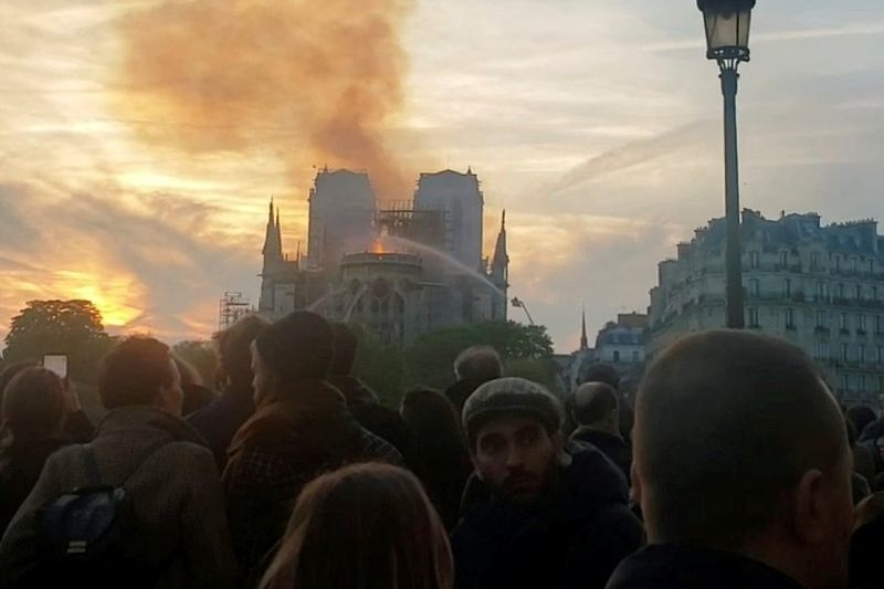 People gather as firefighters spray water to extinguish flames as the Notre Dame Cathedral burns in Paris, France April 15, 2019 in this still image taken from social media video. Alexandre Brandao via REUTERS