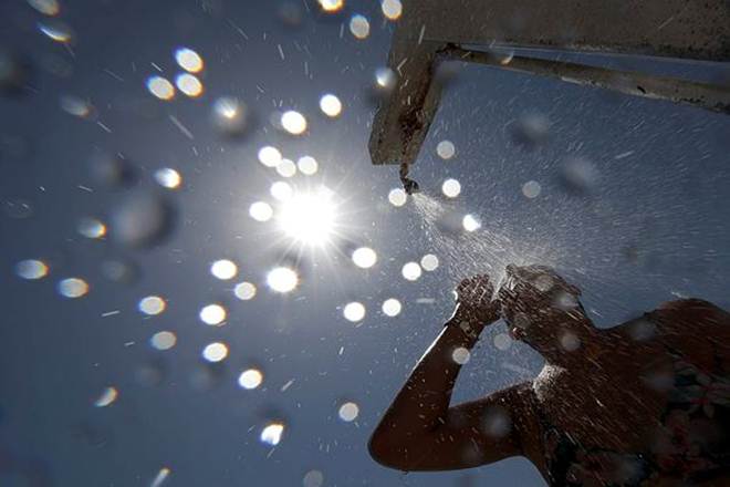 A woman stands under a shower on the beach in Nice as a heatwave hits much of France. (REUTERS)