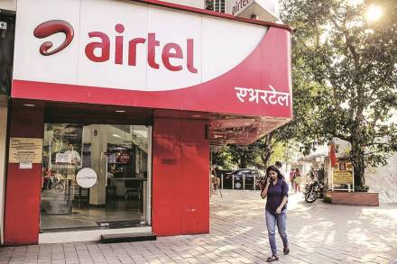A pedestrian using a mobile phone walks past a Bharti Airtel Ltd. store in Mumbai, India, on Sunday, Jan. 19, 2020. Telecom companies including Bharti and Vodafone Idea Ltd. have sought more time from India's top court to pay $13 billion in past dues as they plan to negotiate with the government, people with knowledge of the matter said. Photographer: Dhiraj Singh/Bloomberg