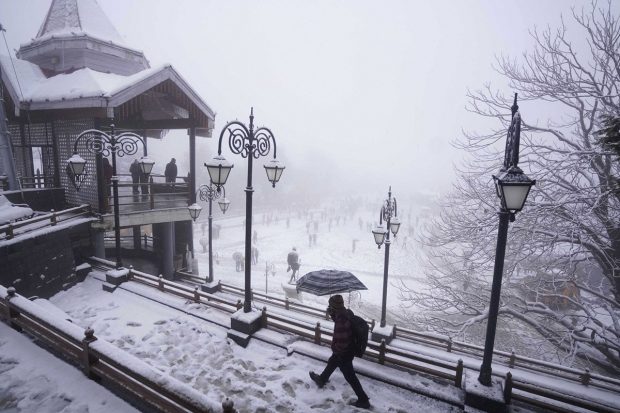A man walks at Ridge during snowfall in Shimla. (PTI Photo)