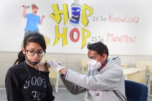 A health worker administers a dose of COVID-19 vaccine to a teenager in New Delhi. (PTI Photo)