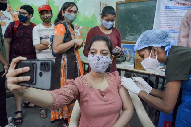 Thane: A student takes a selfie as a health worker administers a COVID-19 vaccine to teenagers in Thane. (PTI Photo)