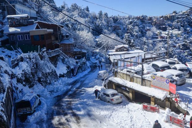 People walk on a snow covered road after heavy snowfall in Shimla. (PTI Photo)