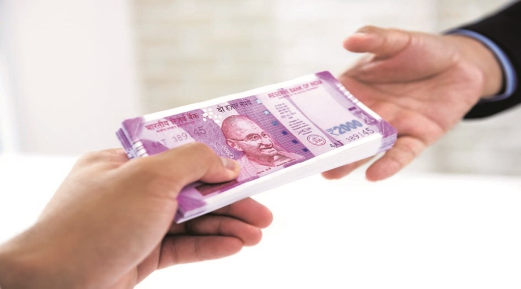 Businessman handing over wad of crisp new Indian rupee banknote money to his partner against white blur background
