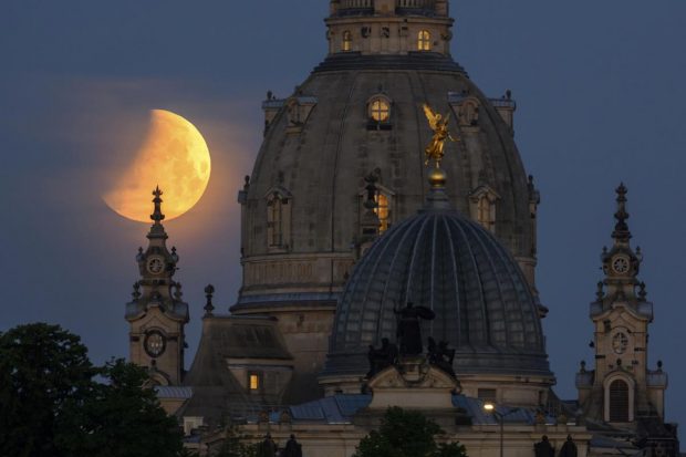 The moon sets in the morning during a partial lunar eclipse behind the Frauenkirche and the dome of the Kunstakedmie with the angel 
