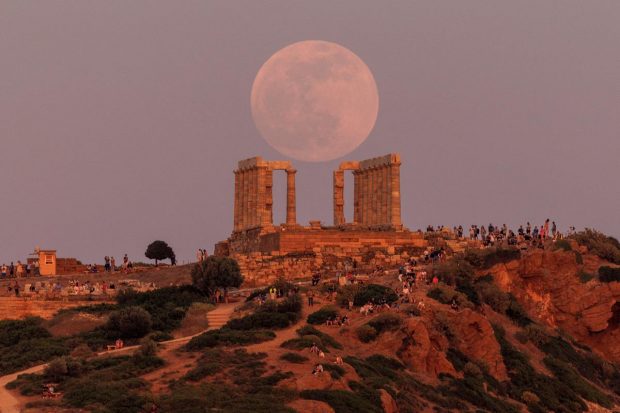 People watch a full moon, known as the 