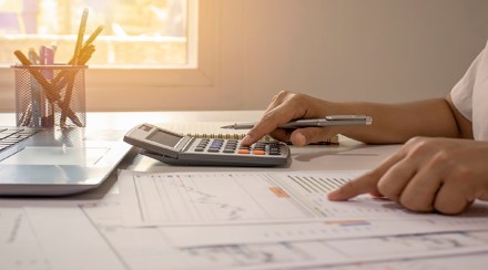 Close-up of businessmen or accountants holding a pen and pressing on the calculator to calculate business information, accounting documents, business ideas.
