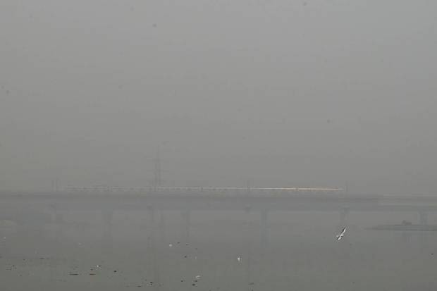 A metro train runs on a bridge enveloped by smog and haze in New Delhi. (AP Photo)