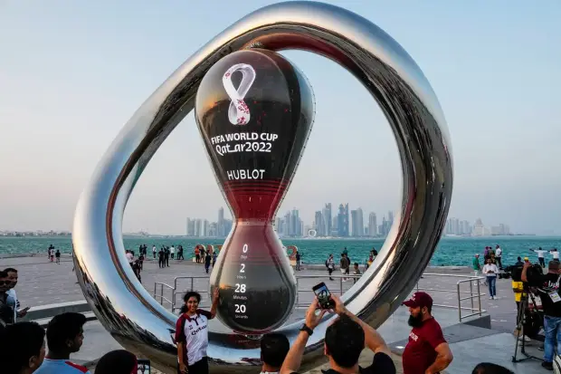 A woman poses for a picture next to the World Cup's count down clock ahead of the World Cup, group A soccer match between Qatar and Ecuador, in Doha, Qatar. (AP Photo)