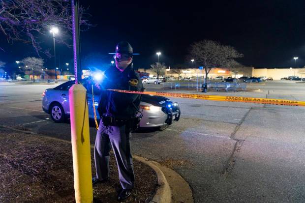 A Virginia State Trooper re-ties crime scene tape as law enforcement work the scene of a mass shooting at a Walmart. (AP Photo)