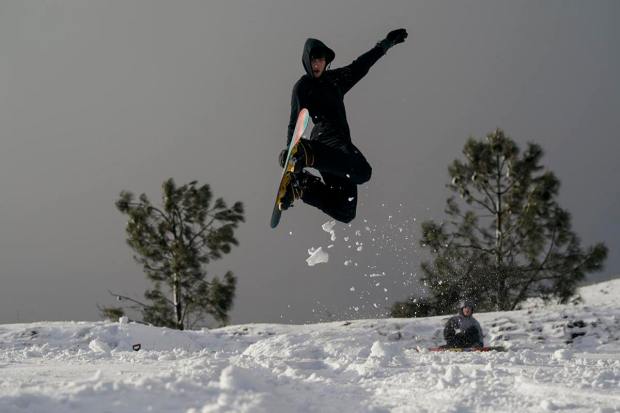 Ryan Rohani, 17, snowboards down a hill while visiting Mount Diablo State Park in Walnut Creek, Calif., Monday, Feb. 27, 2023. In California, the National Weather Service said a series of winter storm systems will continue moving into the state through Wednesday after residents got a brief break from severe weather Sunday. (AP Photo/Godofredo A. Vásquez)