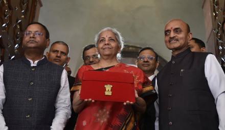 Indian Finance Minister Nirmala Sitharaman, in red, poses for the media holding a pouch containing a digital tablet, with Junior finance ministers Pankaj Chaudhary, left, and Bhagwat Kishanrao Karad, before presenting the federal budget for the financial year 2023-24 in the Parliament in New Delhi, India, Wednesday, Feb. 1 2023. (AP Photo)