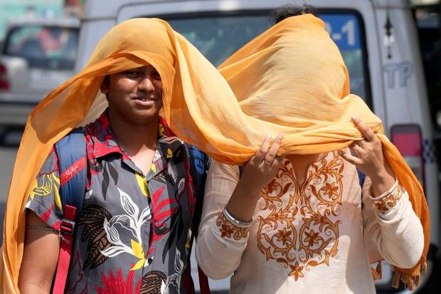 Pedestrians cover themselves with a scarf to get protected from scorching sun as they walks on a city street during a hot summer day in Kolkata. (PTI)