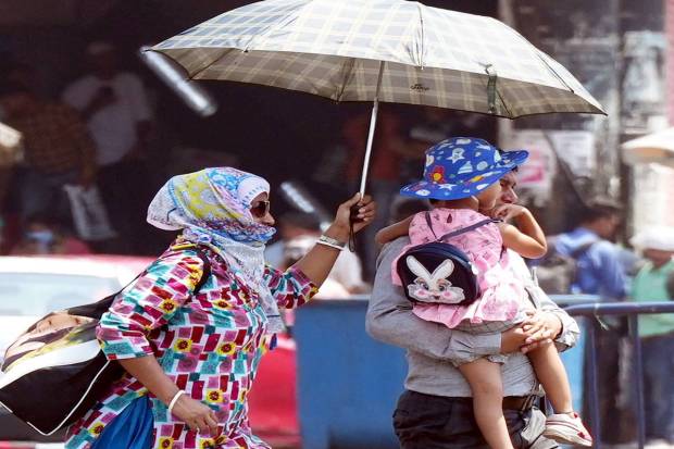 Pedestrians use umbrellas to protect themselves from scorching sun during a hot summer day, in Kolkata (PTI)