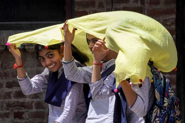Students use a scarf to shield themselves from the hot summer sun, in Amritsar. (PTI)