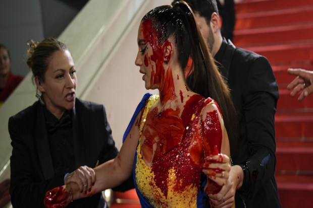 A person, in Ukrainian colours, smeared in a red substance is removed by security at the premiere of the film 'Acide' at the 76th international film festival, Cannes, southern France. (AP Photo)