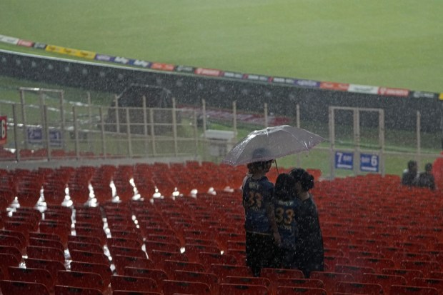 Spectators take shelter under an umbrella as it rains after the delay in start of the play for the Indian Premier League final cricket match between Chennai Super Kings and Gujarat Titans in Ahmedabad on May 28, 2023. (Image/AP)