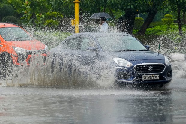  Commuters wade through a waterlogged road during Monsoon rainfall in New Delhi. (Image: PTI)