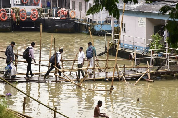 Guwahati: Commuters walk on a temporary bamboo bridge to board a ferry after an increase in water-level of the Brahmaputra river, in Guwahati, Thursday, June 15, 2023. (PTI Photo)