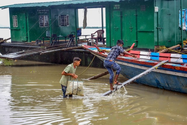 Tezpur: Fishermen carry food and essentials to his boat on the flooded bank of the river Brahmaputra as it rains constantly in Assam, in Tezpur, Saturday, June 17, 2023. (PTI Photo)