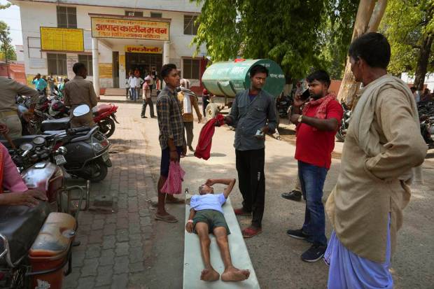 An elderly person suffering from heat related ailment lies on a stretcher waiting to get admitted outside the overcrowded government district hospital in Ballia, Uttar Pradesh state, India. (AP Photo)