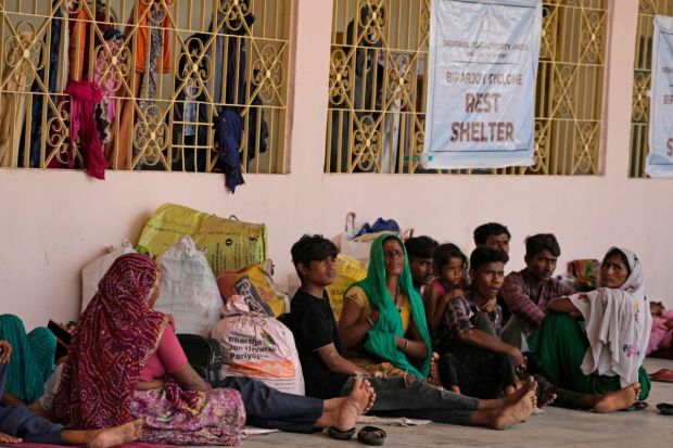 People evacuated from Kandla port, in preparation of Cyclone Biparjoy, rest at a shelter in Gandhidham, India. Authorities on Monday halted fishing activities, deployed rescue personnel and announced evacuation plans for those at risk. (Photo Credits: AP)