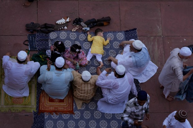 A family sits and talk after offering Eid al-Adha prayers at the Jama Masjid. (Image: AP)