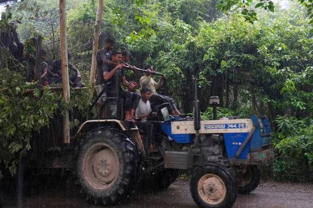 A group of Indian men ride on a tractor under heavy rain in Kotdwar district of Uttarakhand. (AP Photo)