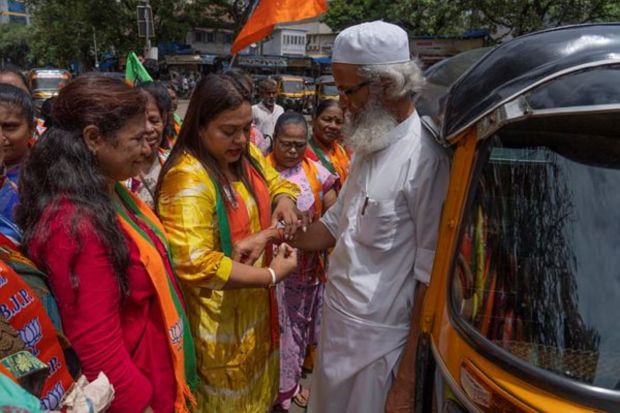 A supporter of the ruling Bharatiya Janata Party (BJP) ties a 'rakhi' on the wrist of a Muslim auto driver outside a railway station in Mumbai on Tuesday. (AP Photo)