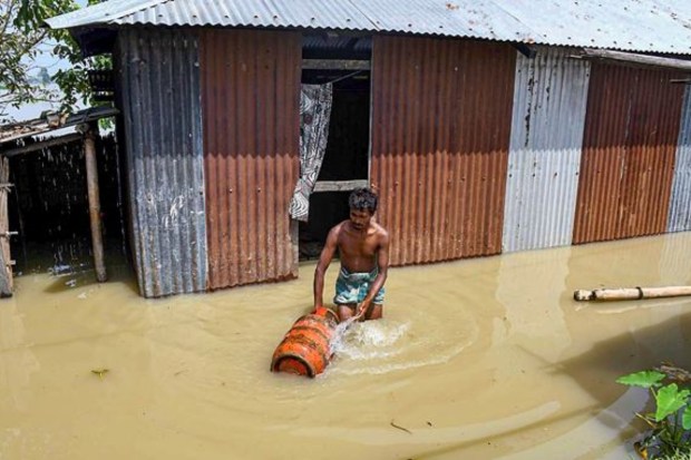 A man carries an LPG cylinder in a flood-affected area on August 30. (Image: PTI)