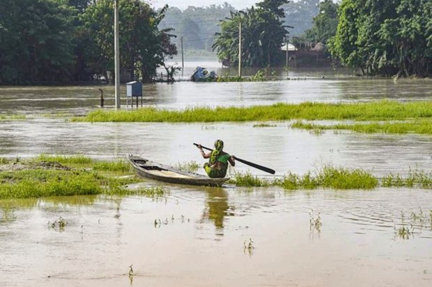  A woman on a boat moves through a flooded area, in Morigaon district on August 30. (Image: PTI)