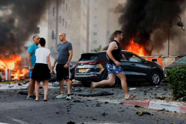 People react on the road, in the aftermath of rocket barrages that were launched from Gaza, in Ashkelon. (Image/Reuters)