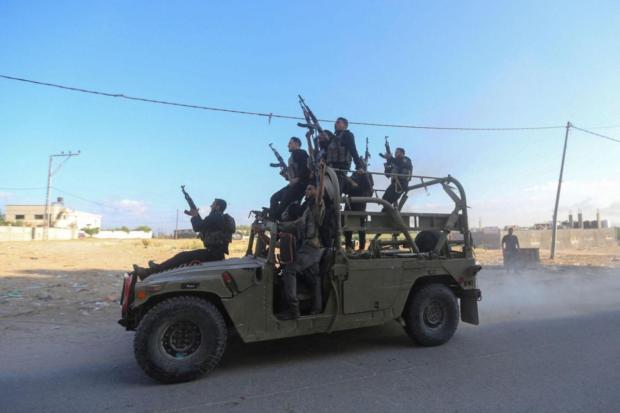 Palestinian militants ride an Israeli military vehicle that was seized by gunmen who infiltrated areas of southern Israel, in the northern Gaza Strip. (Image/Reuters)