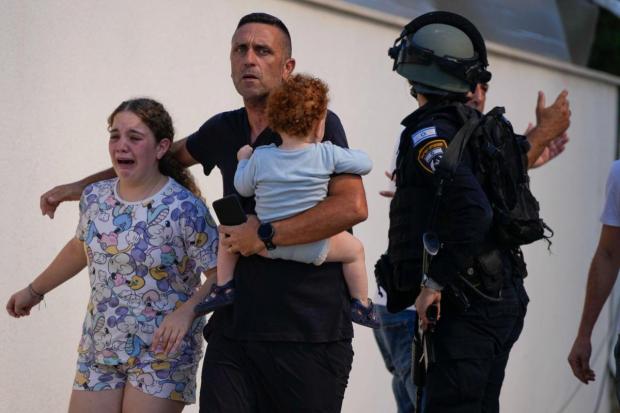 Israeli police officers evacuate a family from a site hit by a rocket fired from the Gaza Strip, in Ashkelon, southern Israel. (Image/AP)