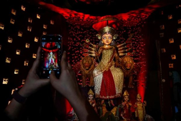 A devotee takes picture of an idol of Hindu goddess Durga at a temporary worship venue in the early hours of the final day of Durga Puja festival in Kolkata on October 24. (Image: AP)
