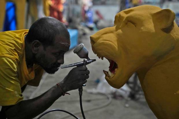 An artisan sprays color on a clay idol of a tiger, the animal that Hindu Goddess Durga rides on, ahead of Durga Puja festival in Hyderabad. (AP Photo)
