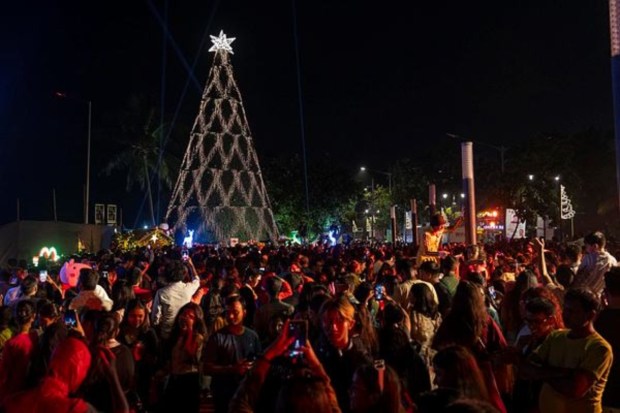 People crowd in front of a decorated Christmas tree at a promenade on the eve of Christmas in Mumbai on December 24. (AP)